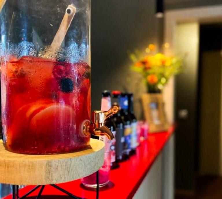 Sangria-Behälter mit Früchten und Getränkeauswahl steht auf einem roten Tresen im Haus am See Mustin.