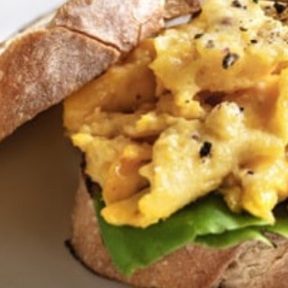 Sandwich mit gerührten Eiern und frischem Salat auf knusprigem Brot.